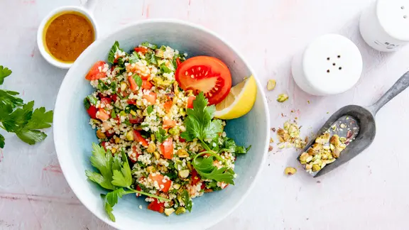 Ein Petersiliensalat, garniert mit Tomate und Zitrone, auf einem Teller.