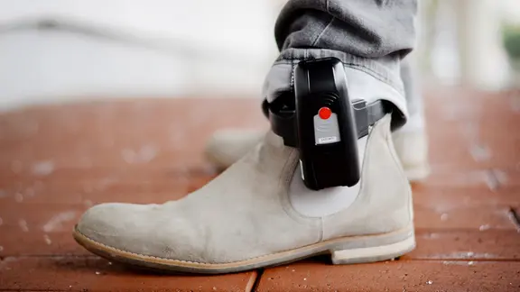 Am Bein eines Mannes ist eine elektronsche Fußfessel befestigt.