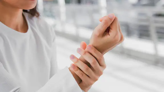 Frau umfasst ihr Handgelenk