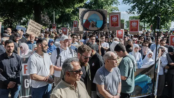 Mehrere Menschen demonstrieren mit Schildern gegen die Schließung der Blauen Moschee in Hamburg.