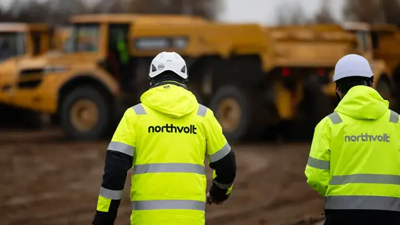 Mitarbeiter der Firma Northvolt stehen auf einer Baustelle.