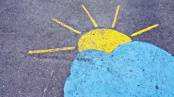 Eine auf Stein gemalte Sonne bahnt sich ihren Weg durch die Wolken. | samuelschalch / photocase.de, samuelschalch Eine auf Stein gemalte Sonne bahnt sich ihren Weg durch die Wolken.