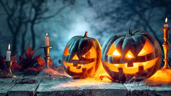 Eine Gruselszene mit Halloween-Kürbissen und Kerzen.
