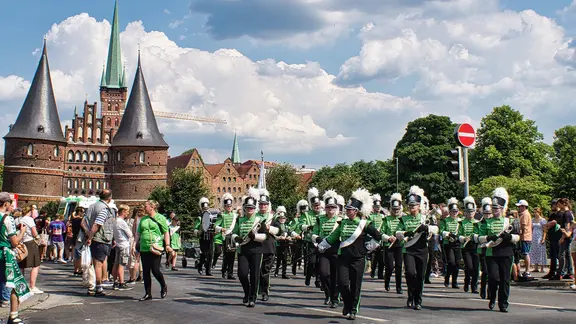 Ein Orchester geht durch eine Lübecker Straße am Holstentor vorbei.