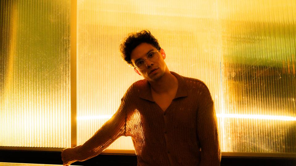 Am 4. Juli steht Kamrad beim NDR Festival in Grömitz auf der Bühne. | Fabian Süggeler, Fabian Süggeler Der Musiker Kamrad vor einer belichteten Wand.