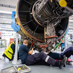 Drei Männer arbeiten in einer Werkstatt von Lufthansa Technik am Triebwerk eines Flugzeuges.