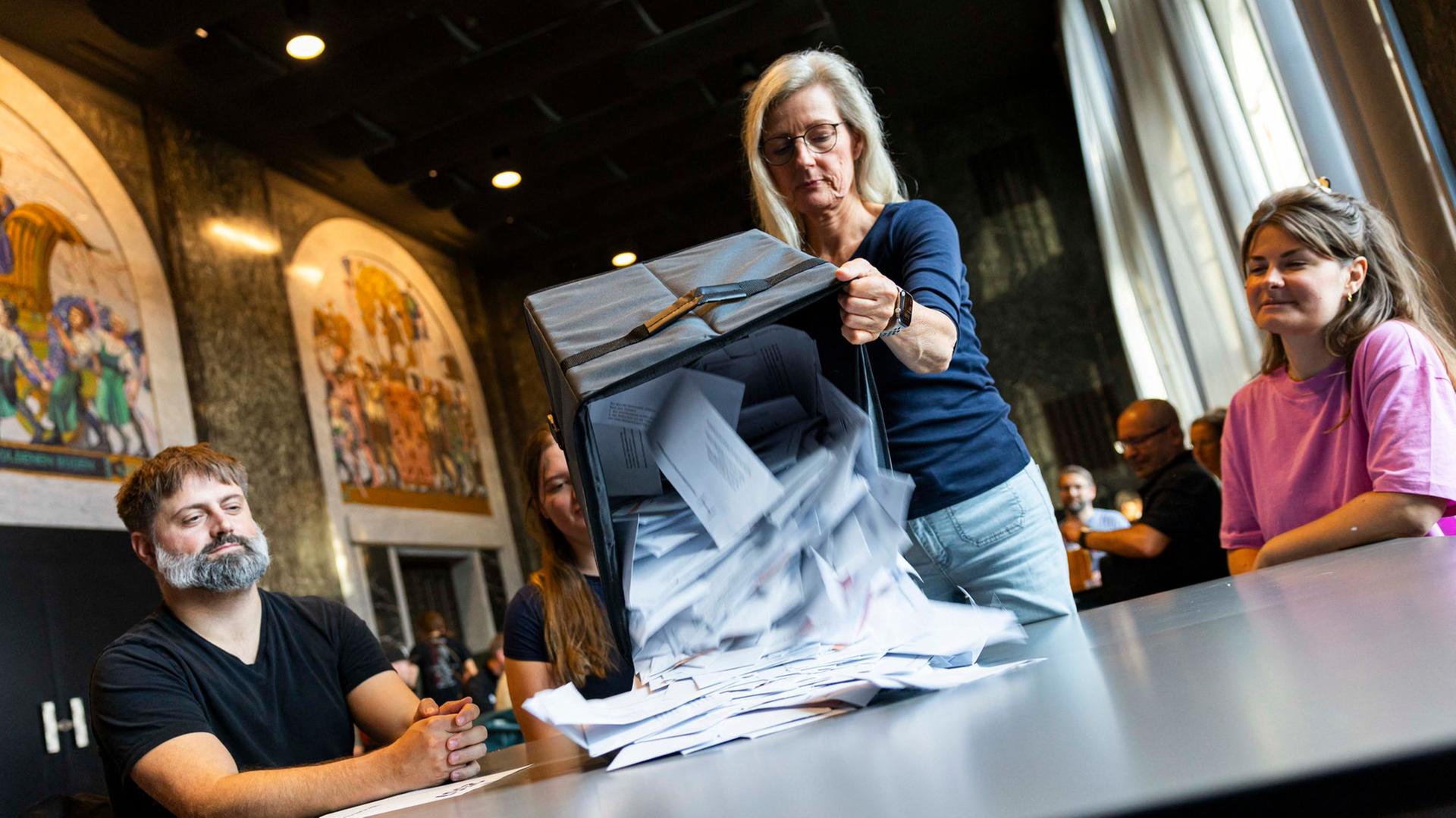 Eine Wahlhelferin schüttet nach der Wahl Briefwahlunterlagen auf einen Tisch. | dpa-Bildfunk, Michael Matthey
