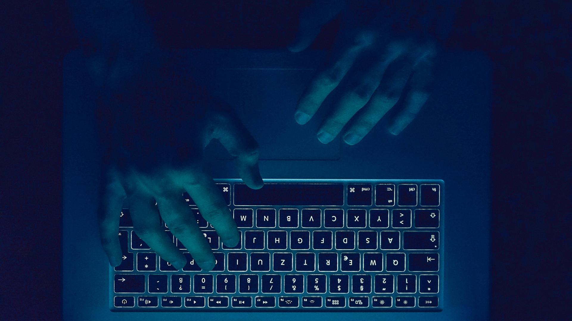 Zwei Hände über einer Tastatur im Dunklen. | Photocase, PolaRocket