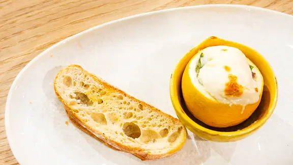 Überbackene Sardellenfilets in einer Zitronenschale serviert.