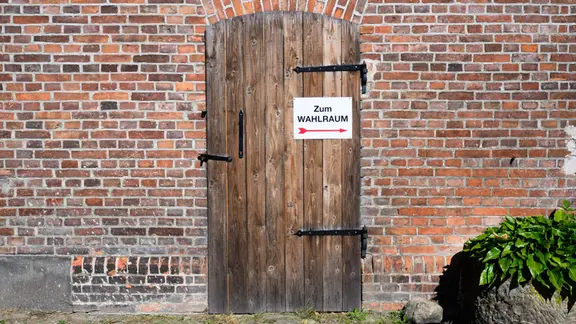 Wegweiser zu einem Wahllokal auf einem Hof in der Region Hannover. | dpa, Julian Stratenschulte Wegweiser zu einem Wahllokal auf einem Hof in der Region Hannover.