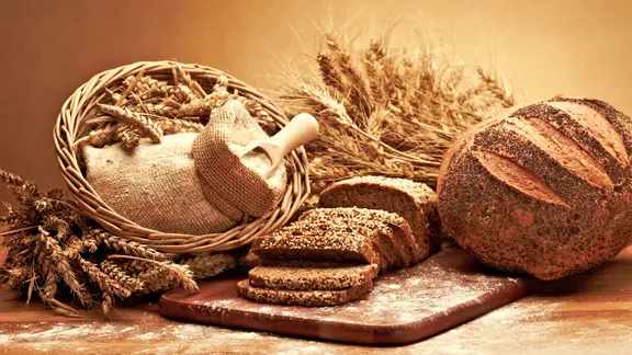 Brot und Getreide auf einem Brett arrangiert.