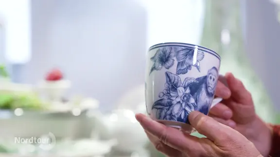 Jemand hält eine blau bemalte Porzellan-Tasse in den Händen.