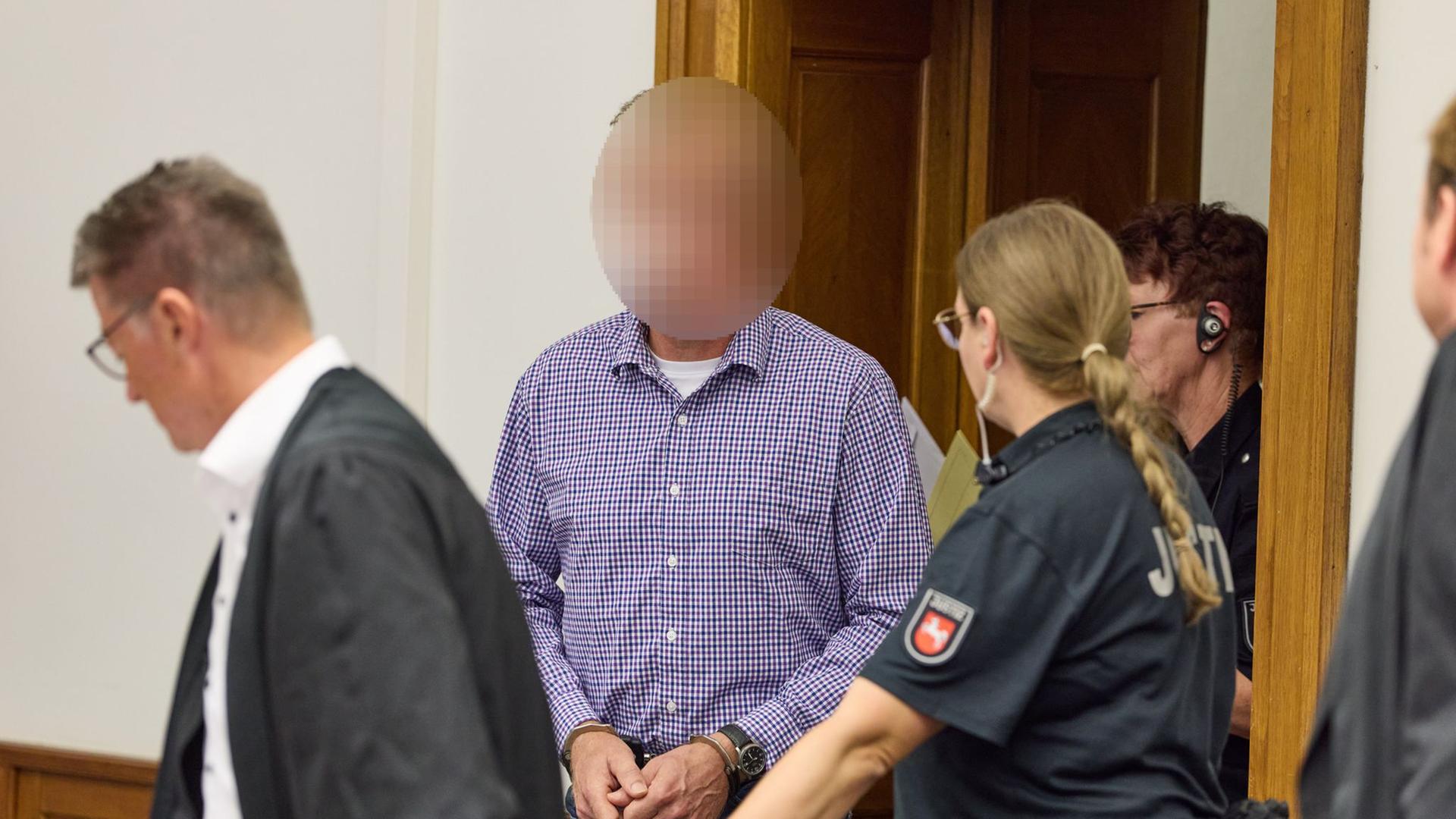 Ein Angeklagter wird mit Handschellen vor Beginn des Prozesses in den Gerichtssaal des Landgerichts Lüneburg geführt. | dpa-Bildfunk, Georg Wendt
