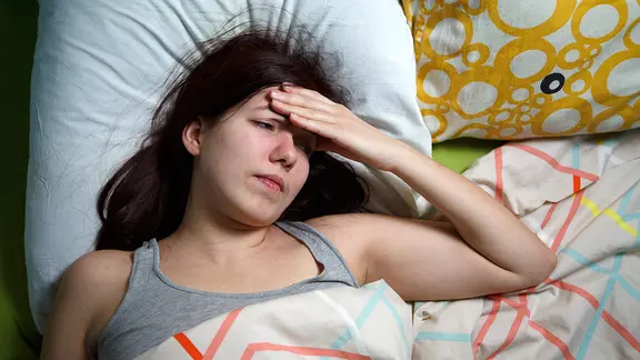 Junge Frau im Bett schaut verzweifelt und legt die Hand gegen die Stirn. | Fotolia.com, Sergey Junge Frau im Bett schaut verzweifelt und legt die Hand gegen die Stirn.