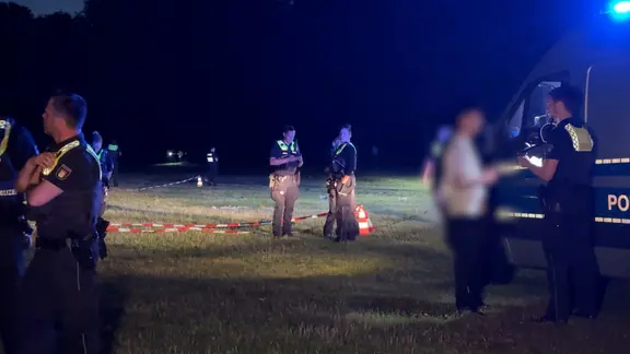 Polizisten beleuchten nach einer Auseinandersetzung im hamburger Stadtpark eine Wiese.