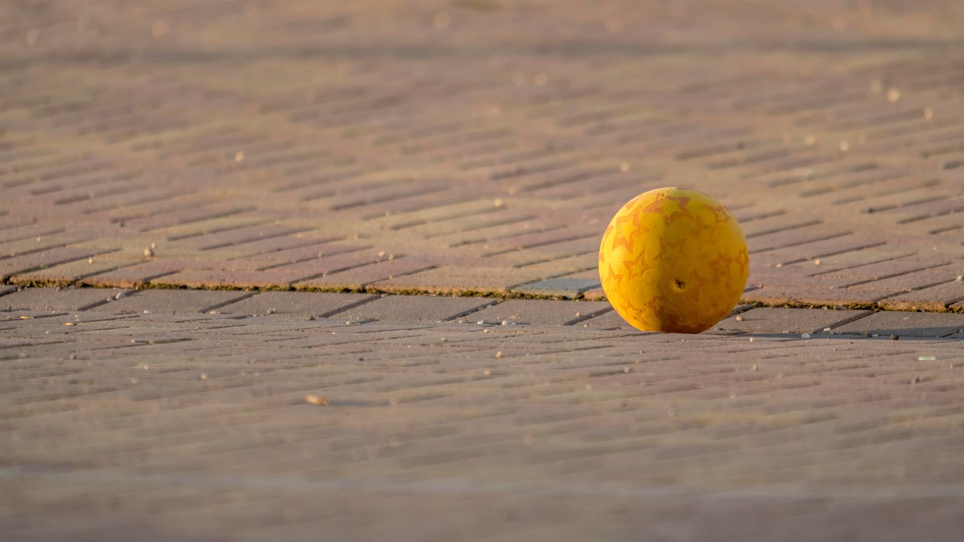 Ein Ball liegt auf einem gepflasterten Platz. | picture alliance/vizualeasy | Janny