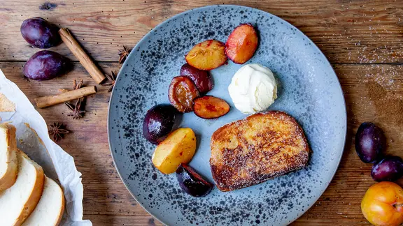 Armer Ritter mit gebackenen Pflaumen auf einem Teller serviert.