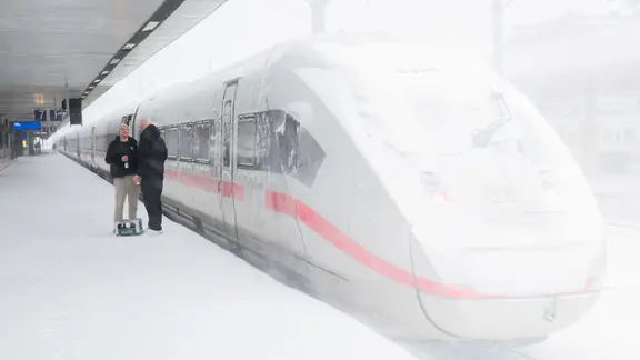 Zwei HSV-Fans stehen mit einer Kiste Bier vor einem ICE der Deutschen Bahn in Hannover. 