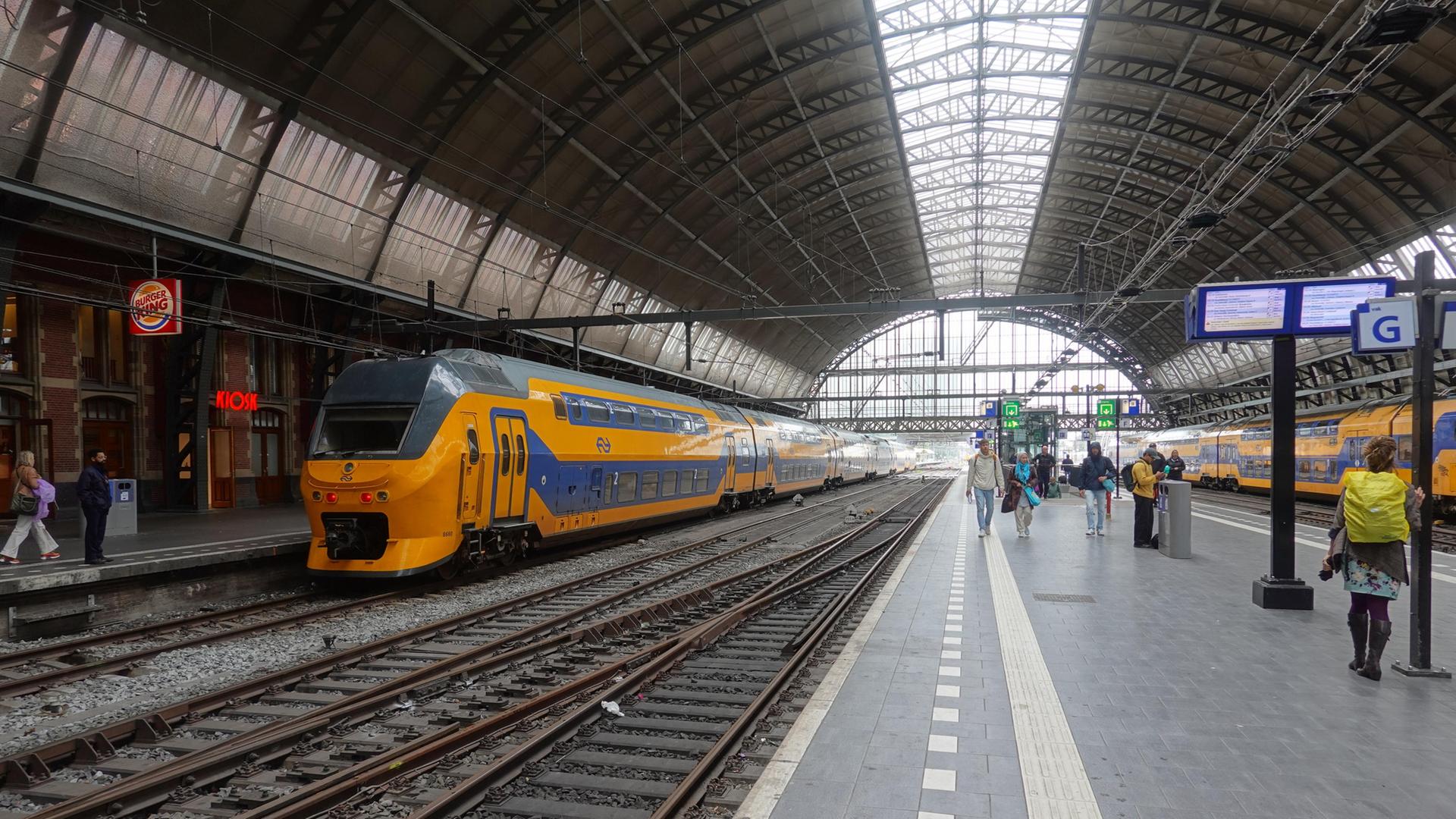 Ein Zug steht im Hauptbahnhof Amsterdam am Gleis. | picture alliance / CHROMORANGE | www.viennaslide.com