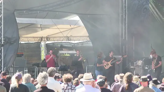 Eine Band spielt vor Publikum auf einer Bühne.