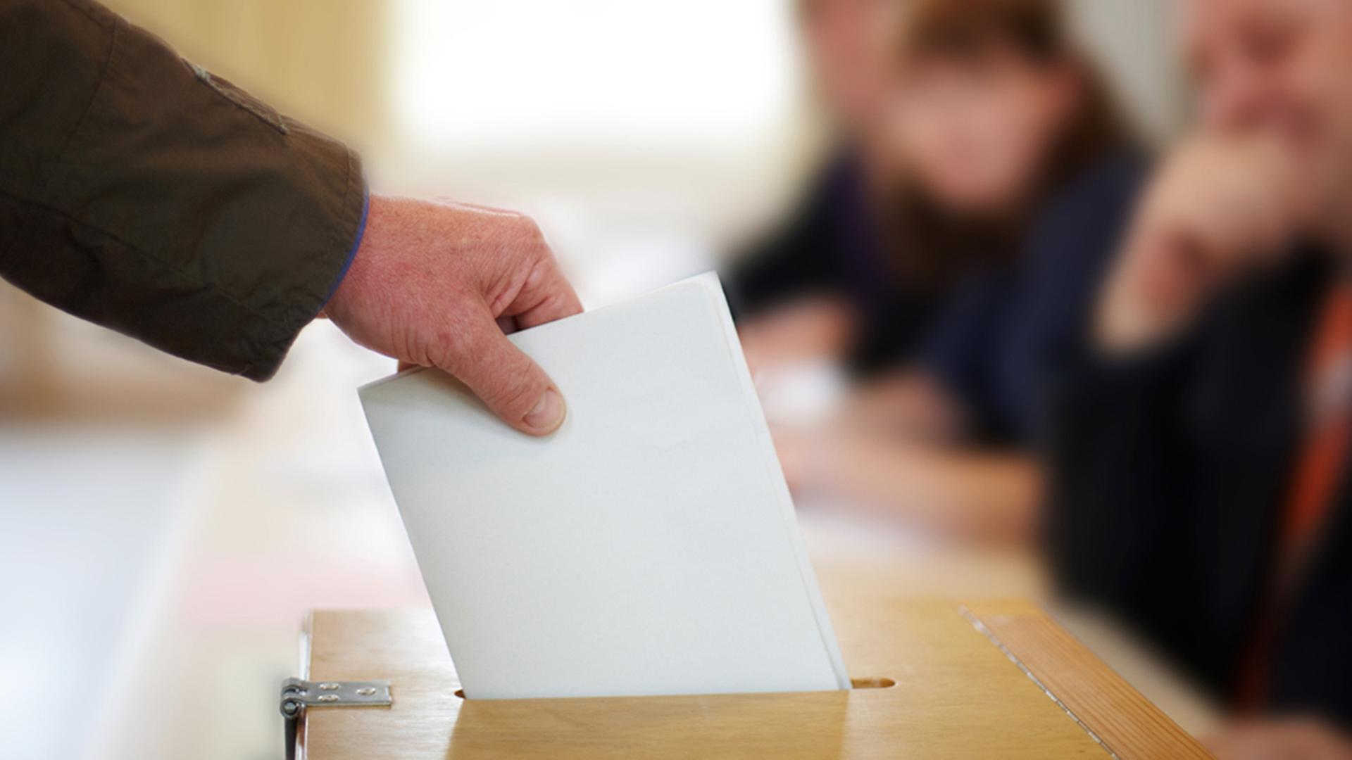 Hand wirft Umschlag in Wahlurne | Fotolia.com, Christian Schwier