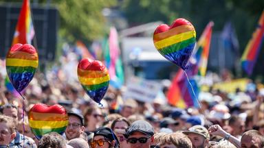 Teilnehmer halten beim Umzug zum Christopher Street Day (CSD) in Oldenburg Luftballons in Regenbogenfarben.