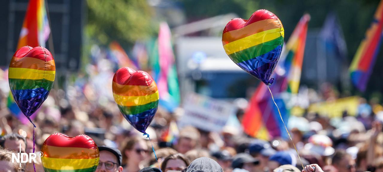 Teilnehmer halten beim Umzug zum Christopher Street Day (CSD) in Oldenburg Luftballons in Regenbogenfarben. | dpa, Focke Strangmann Teilnehmer halten beim Umzug zum Christopher Street Day (CSD) in Oldenburg Luftballons in Regenbogenfarben.