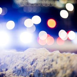 Autos fahren am frühen Morgen eine Straße im Zentrum von Hannover entlang, während Schnee den Fahrbahnrand säumt.