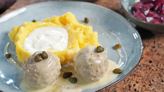 Königsberger Klopse mit Kartoffelpüree und Soße auf einem Teller serviert