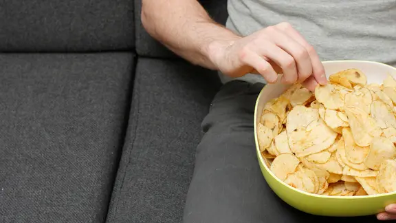 Emotionales Essen: Mann mit Schüssel Chips auf dem Schoß