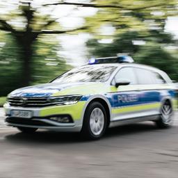 Ein Polizeiauto in Unschärfe fährt mit Blaulicht eine Straße entlang.