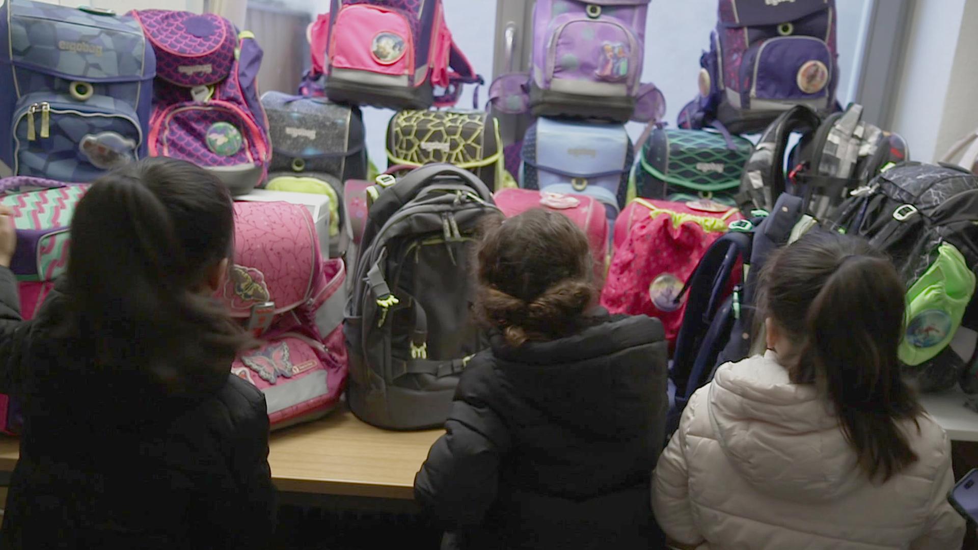 Drei Kinder stehen vor vielen bunten Schulranzen bei einer Spendenaktion in Braunschweig. | NDR