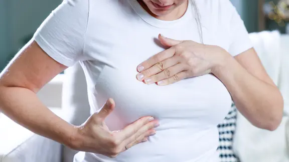 Bruskrebs Symbolbild: Frau tastet Brust ab