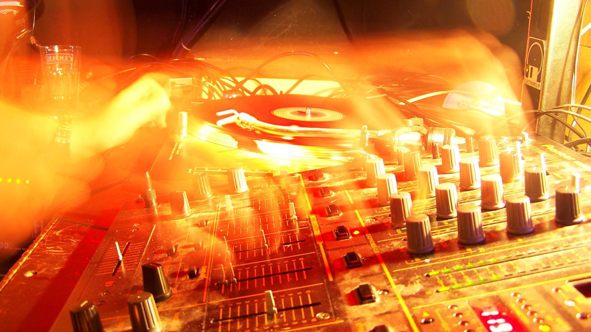 Das Bild zeigt einen Plattenteller und die verschwomme Hand eines DJs. | minimalism / photocase.de, minimalism