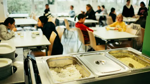 Schüler sitzen in der Mensa beim Mittagessen.