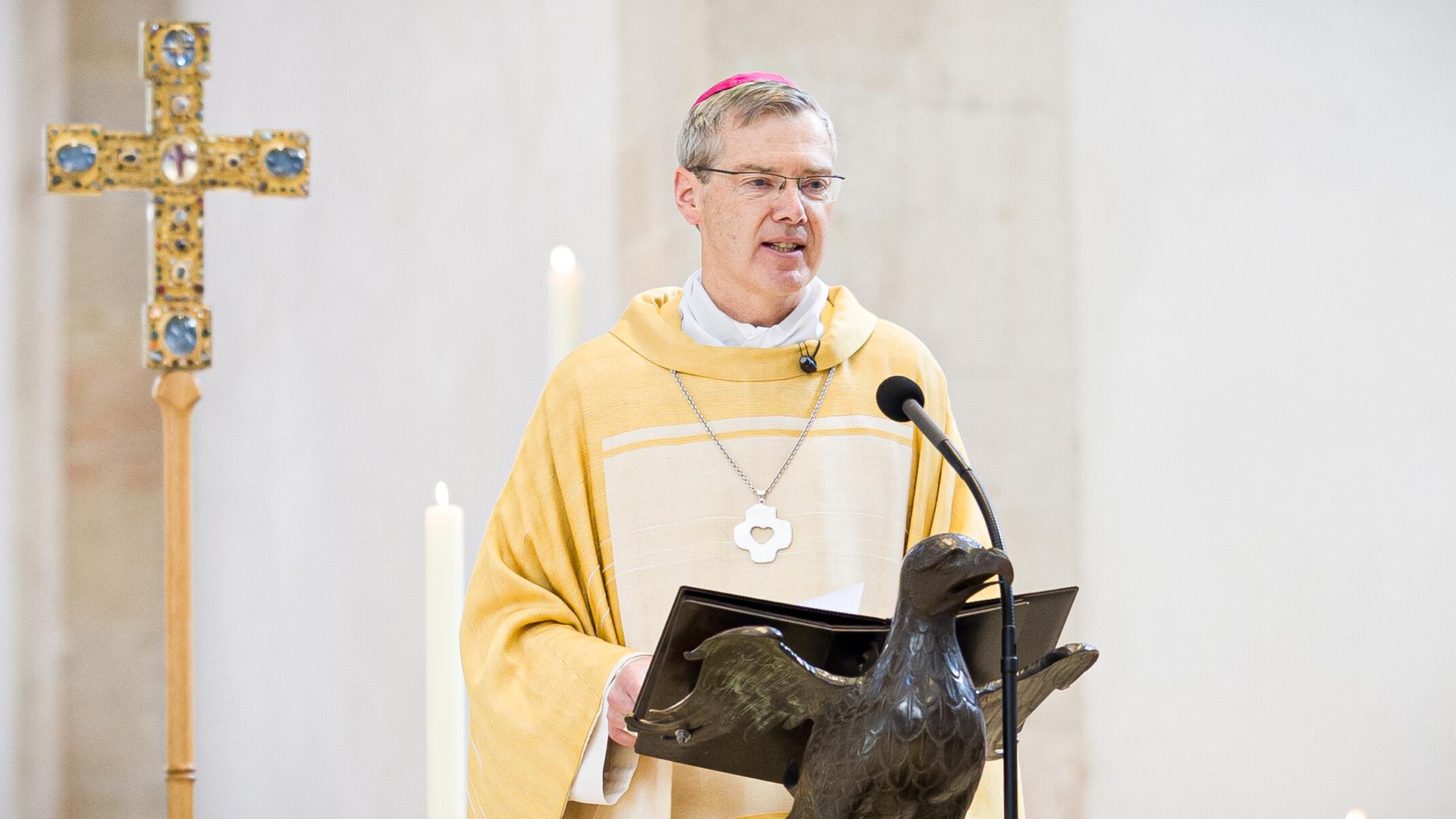 Bischof Heiner Wilmer spricht bei einer Messe in ein Mikrofon, neben ihm steht ein Kreuz. | picture alliance/dpa | Moritz Frankenberg