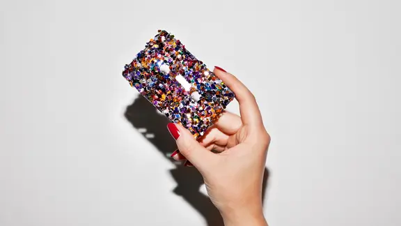 Zu sehen ist eine Hand, die eine glitzernde Kassette hält.