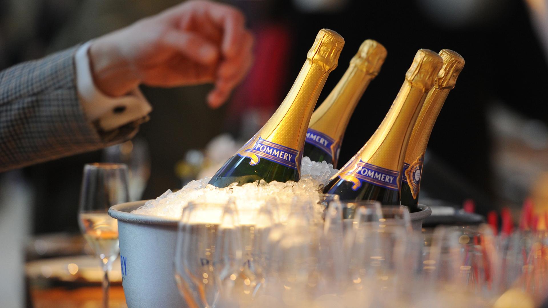Eine Hand greift nach eisgekühlten Champagner-Flaschen | picture alliance / dpa , Jens Kalaene