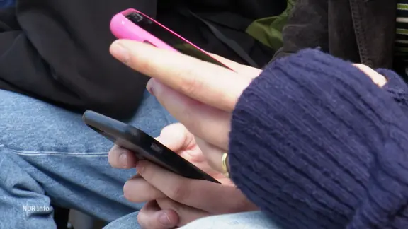 Schülerinnen und Schüler mit Handy in der Hand.
