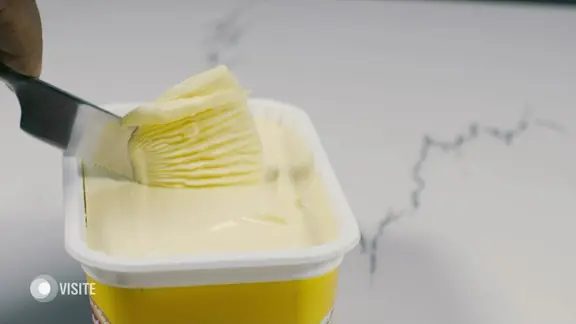 Margarine wird mit einem Messer aus der Packung entnommen.
