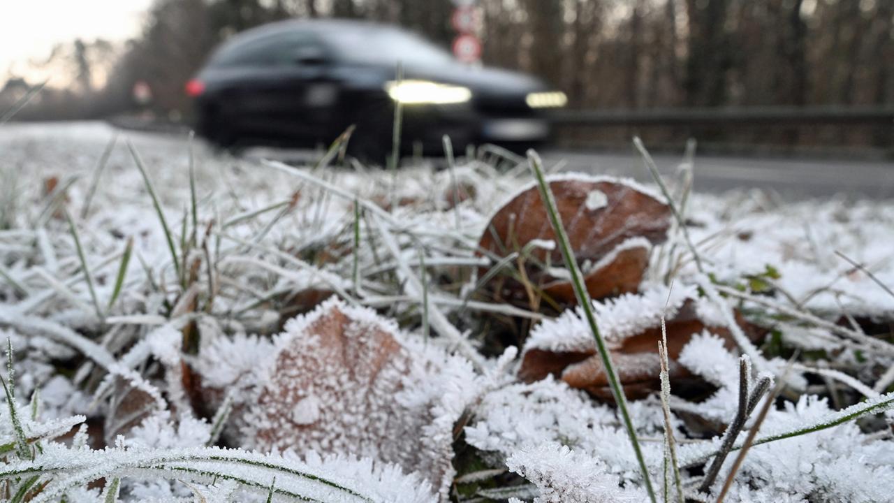 Ein Auto fährt bei frostigem Wetter auf einer Landstraße vorbei