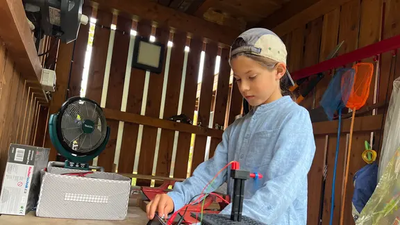 Auch Sohn Leopold Menzel ist von der vernetzten Technik begeistert. Sein Spielzeug wird mit Solarenergie betrieben. | Larissa Messe Ein Junge spielt mit Kindertechnik.