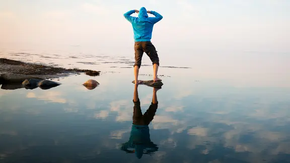 Ein Mann blickt auf die Horizontlinie des Meeres