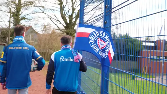 Zwei Fans von Holstein Kiel mit einer Fahne.