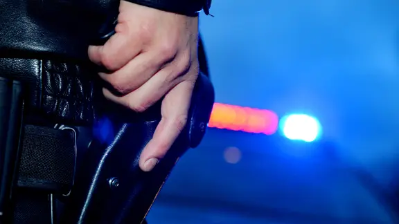 Ein Polizist greift an seine Dienstwaffe