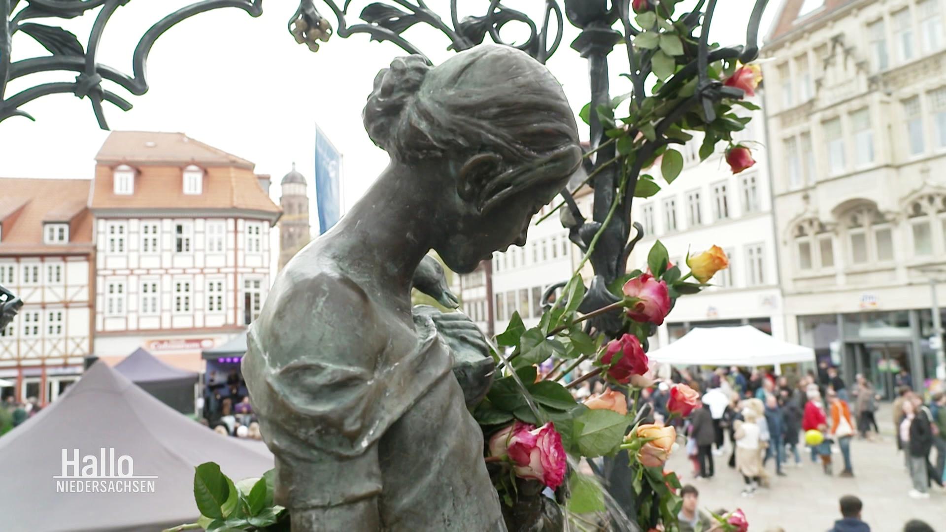 Eine grüne Statue ist mit Blumen geschmückt. | Screenshot