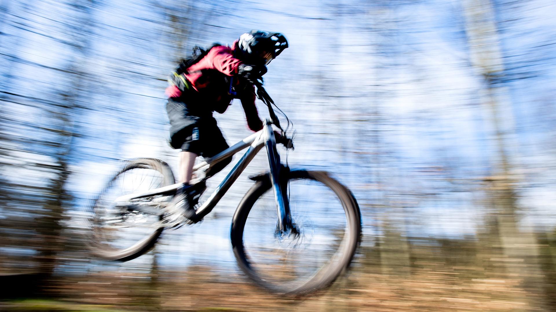 Eine Person springt mit seinem Mountainbike über eine Anhöhe. | picture alliance/dpa, Hauke-Christian Dittrich