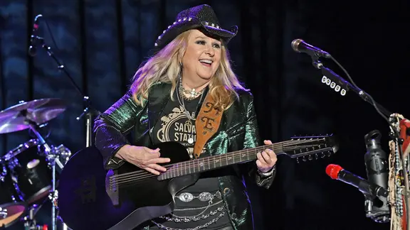 Eine blonde Sängerin mit Cowboy-Hut und Gitarre steht auf der Bühne.