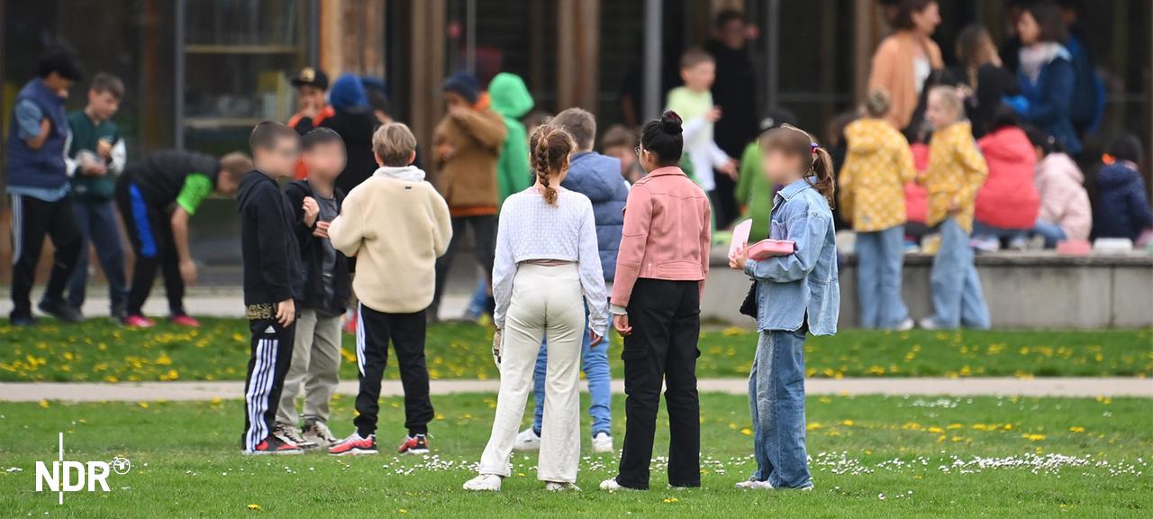 Kinder stehen auf dem Schulhof.