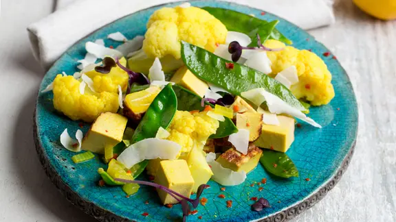 Blumenkohlcurry auf einem Teller, Besteck und Serviette auf einem Tisch. | NDR, Claudia Timmann Blumenkohlcurry auf einem Teller, Besteck und Serviette auf einem Tisch.